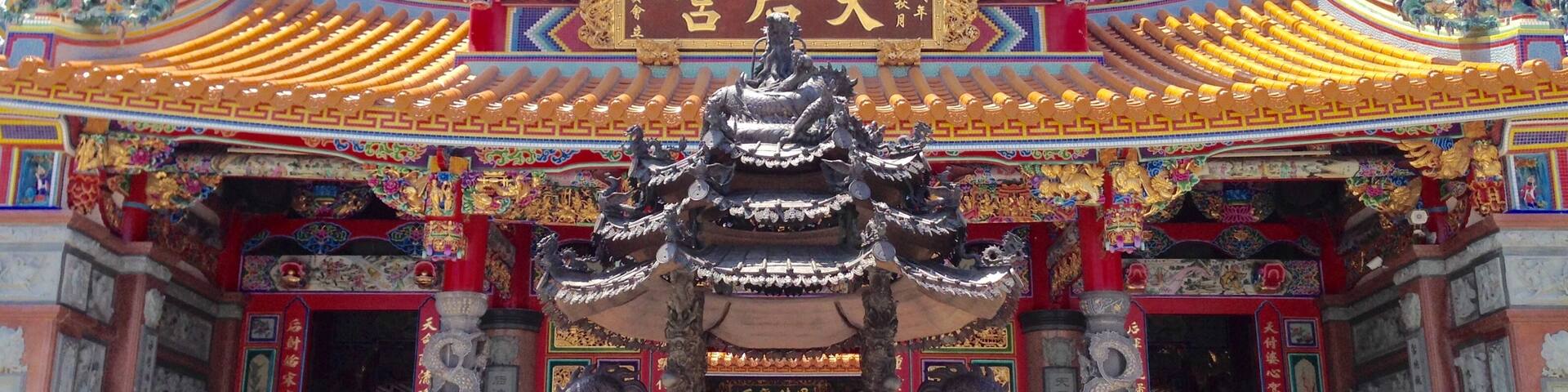 A traditional Chinese temple with ornate dragon decorations and a large bronze incense burner.