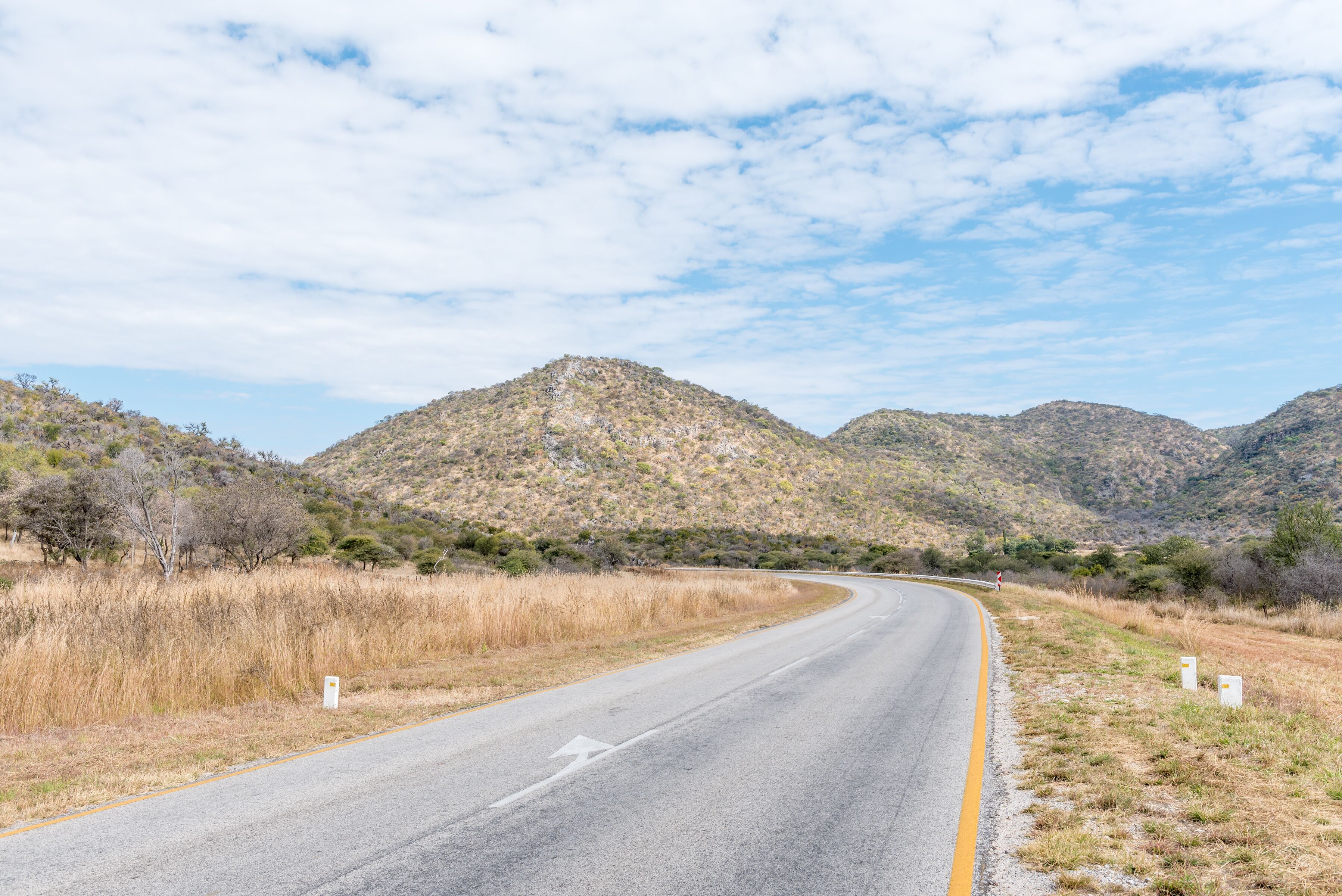 A winding road through a mountainous landscape with sparse vegetation and clear skies.