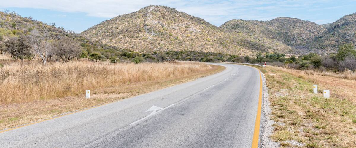 A winding road through a mountainous landscape with sparse vegetation and clear skies.