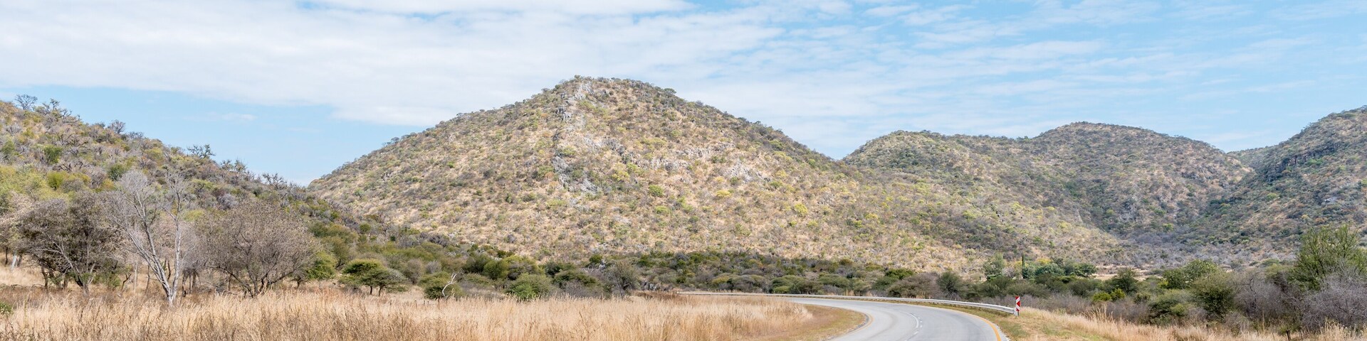 A winding road through a mountainous landscape with sparse vegetation and clear skies.