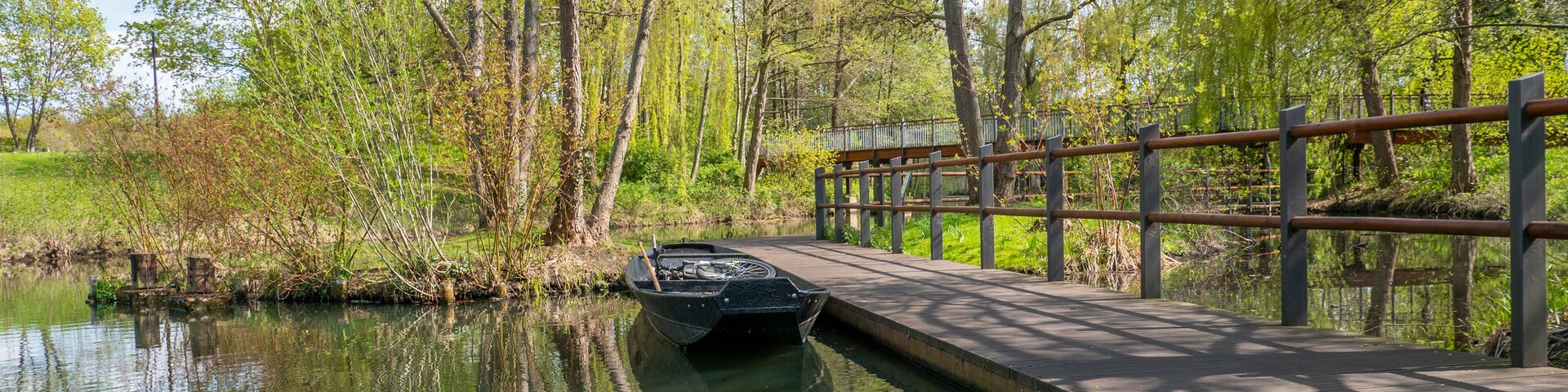 Un puente de madera sobre un río tranquilo, rodeado de abundante vegetación y árboles.