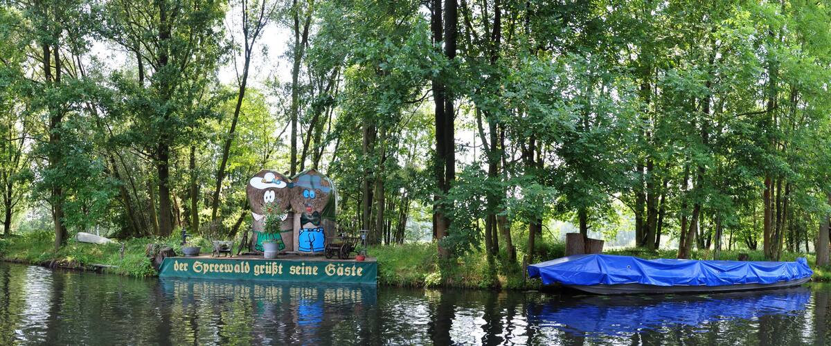 A river with a boat covered in blue tarp and a sign in German.