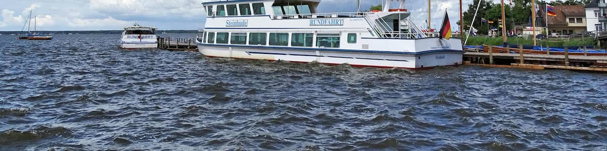 Un bateau blanc, baptisé « Steinhude », était amarré à un quai, sous un ciel dégagé parsemé de nuages.