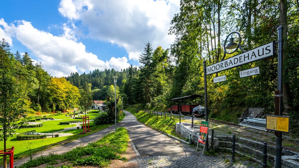 A park with a sign reading "MOORBADEAHUS" and a pathway leading through it.