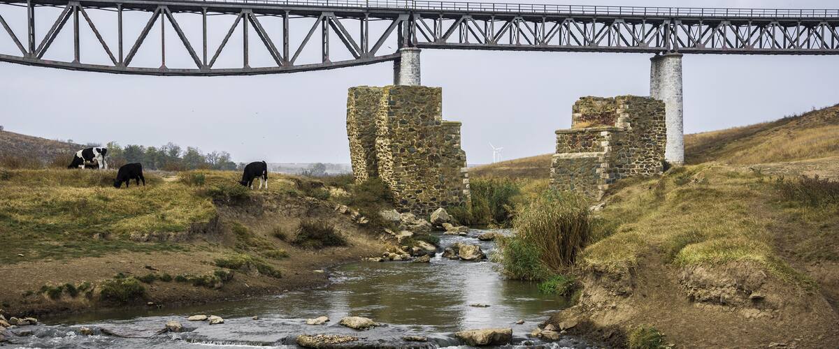 A river with a bridge and stone ruins.