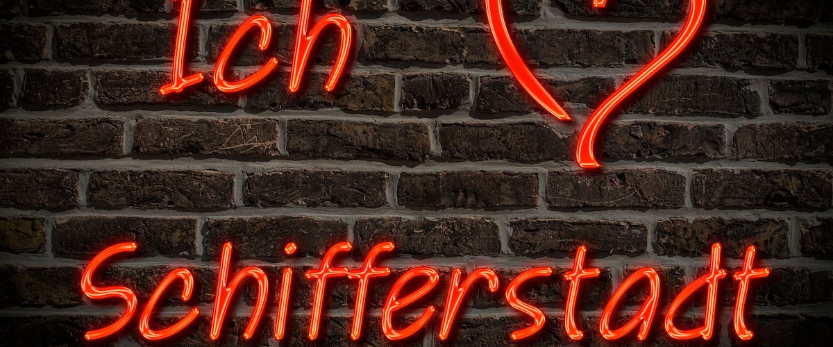 A neon sign with the text "Ich Liebe Schifferstadt" on a brick wall.