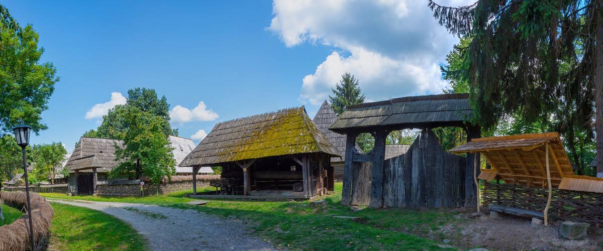 A rural village with traditional wooden houses, a thatched-roof barn, and a wooden fence.
