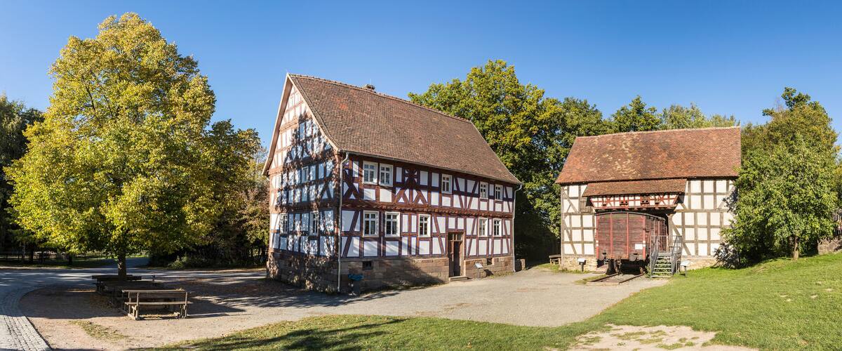 A half-timbered house with a sloped roof and a smaller adjacent building with a flat roof.