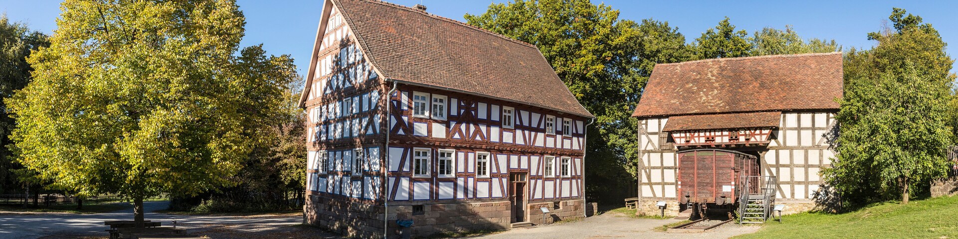 A half-timbered house with a sloped roof and a smaller adjacent building with a flat roof.