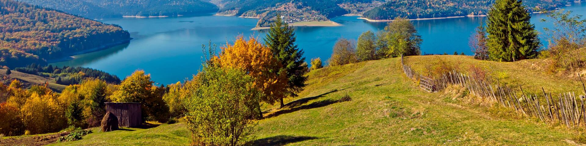 A mountainous landscape with a lake surrounded by forested hills.