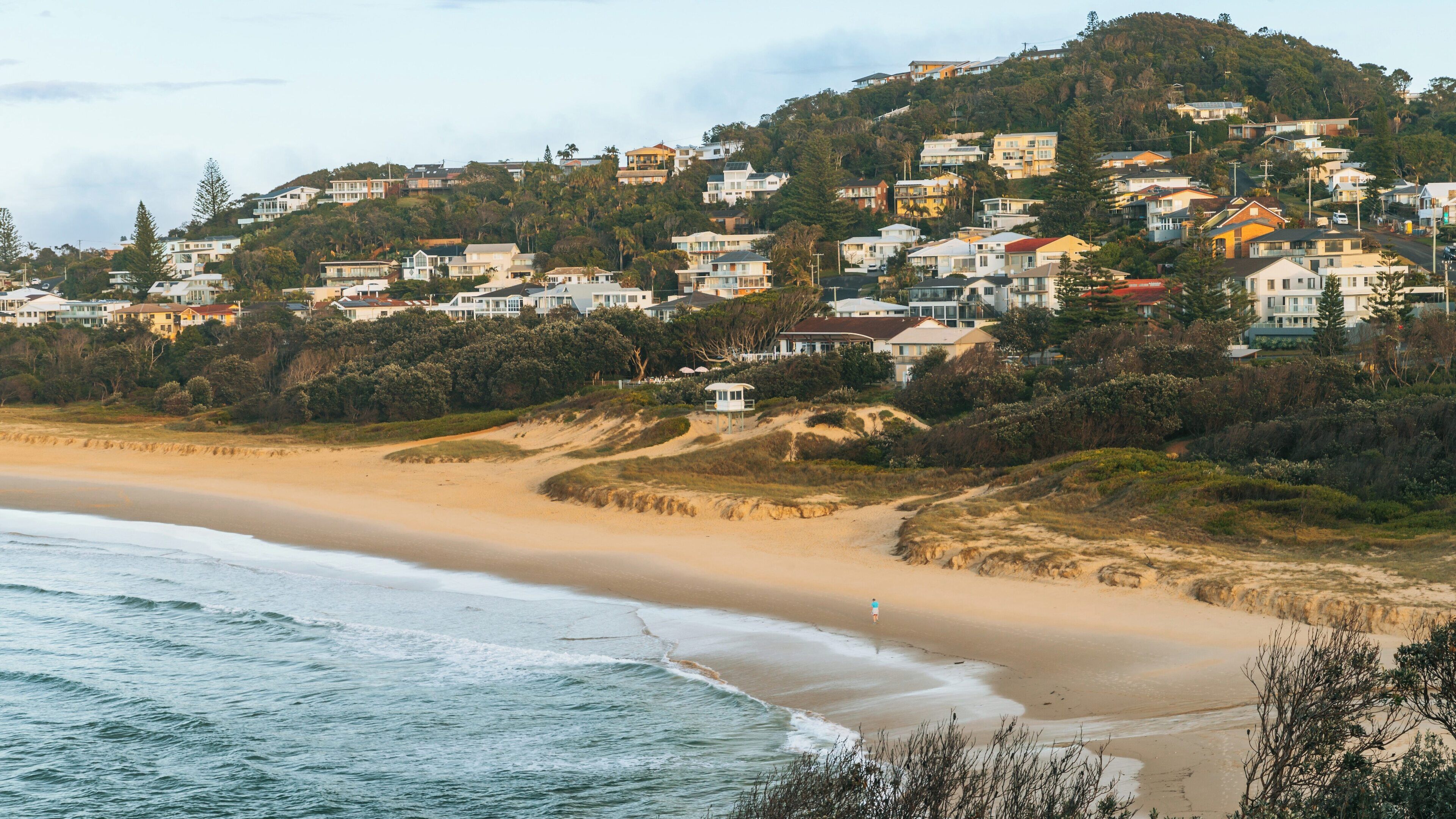 Beautiful Lighthouse Beach in East Ballina, Byron Bay showcasing golden sands and lush greenery during a serene daylight moment