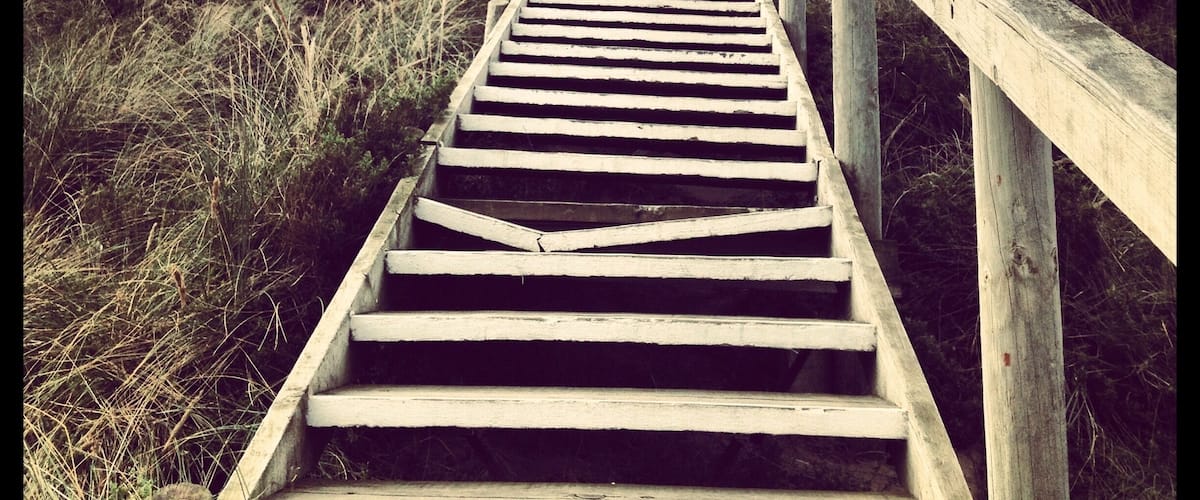 A wooden staircase leading uphill with a guardrail on one side.