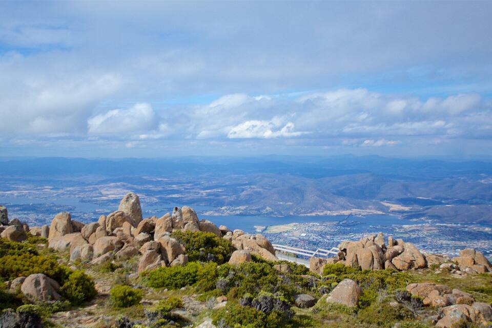 A mountainous landscape with prominent rock formations and a distant cityscape.