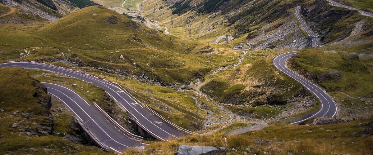 Eine kurvenreiche Bergstraße, umgeben von üppigen grünen Hügeln und einem Tal.