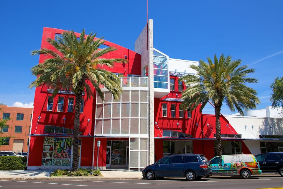 Een rood gebouw met palmbomen, een blauwe auto en een bestelwagen met een kleurrijke reclame.