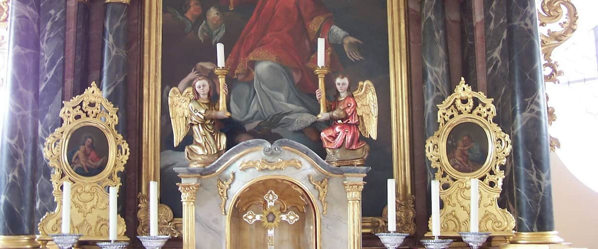 A religious altar with a central painting, gold decorations, and two side altars.