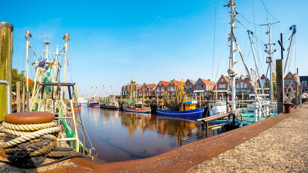 Un port avec des bateaux, une jetée en bois et des bâtiments aux toits rouges.
