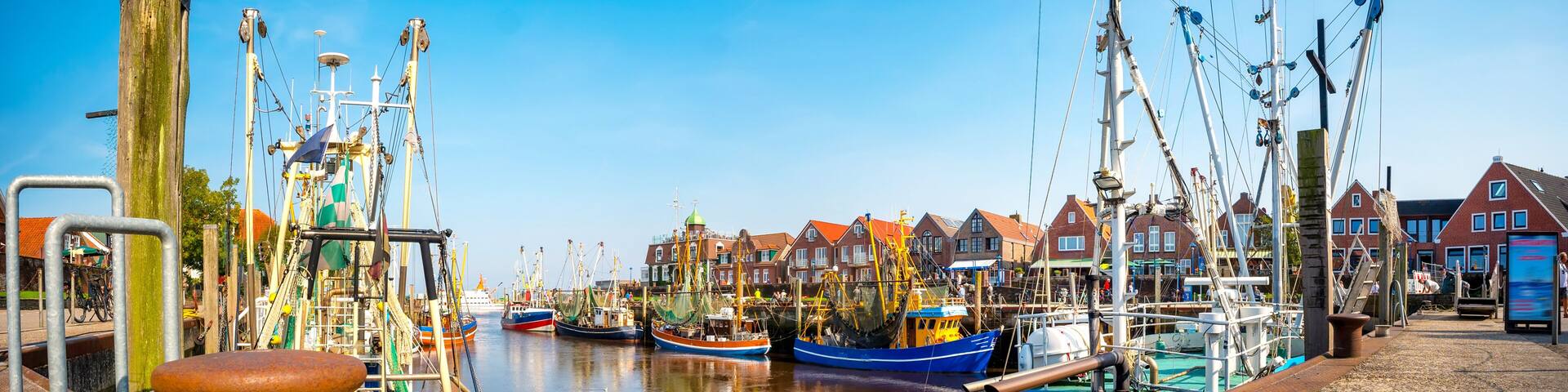 A harbor with boats, a wooden dock, and red-roofed buildings.