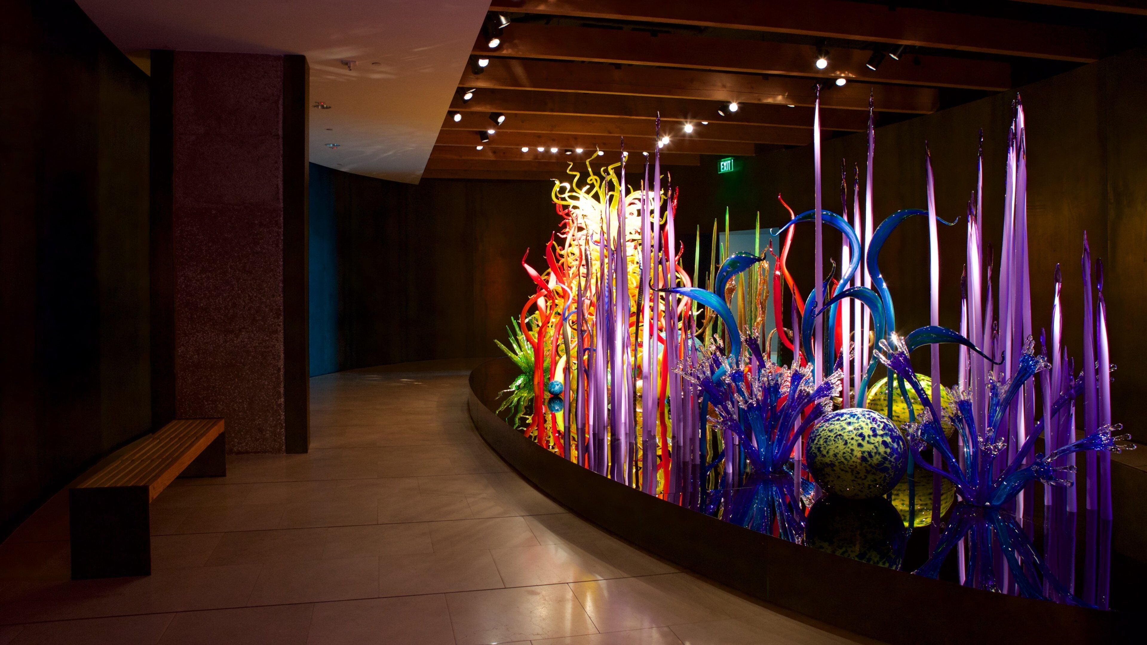 A modern art installation with colorful glass sculptures in a dimly lit hallway.