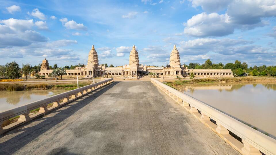 A temple complex with multiple towers and a large body of water in the foreground.