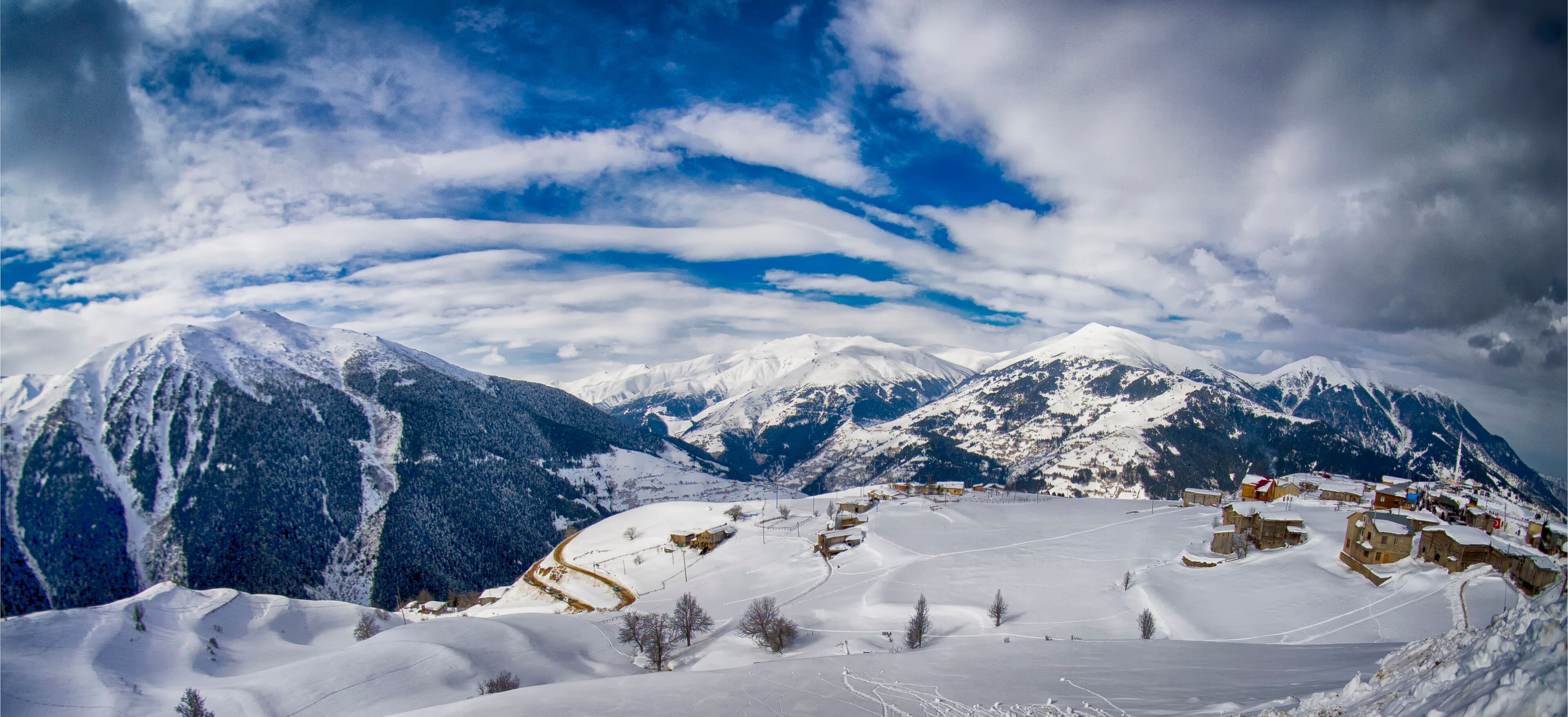 A snow-covered mountain range with a village nestled in the valley.