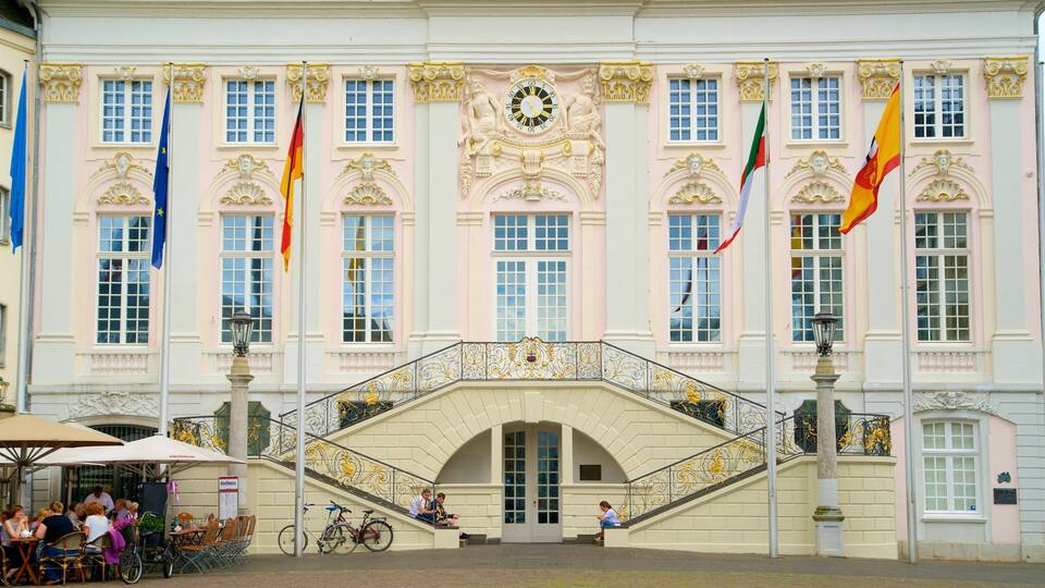 Ein historisches Gebäude mit aufwendiger Architektur, einer Uhr und mehreren Flaggen.