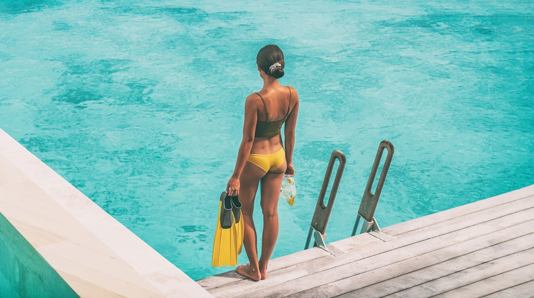 Luxury Bora Bora resort woman going snorkeling from overwater bungalow panoramic. Tahiti paradise destination vacation.