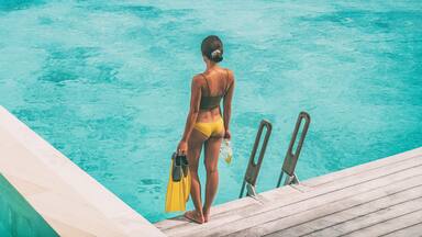 Luxury Bora Bora resort woman going snorkeling from overwater bungalow panoramic. Tahiti paradise destination vacation.