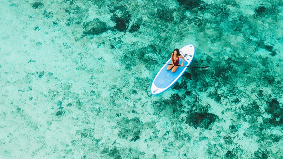 A person on a paddleboard in clear turquoise water.
