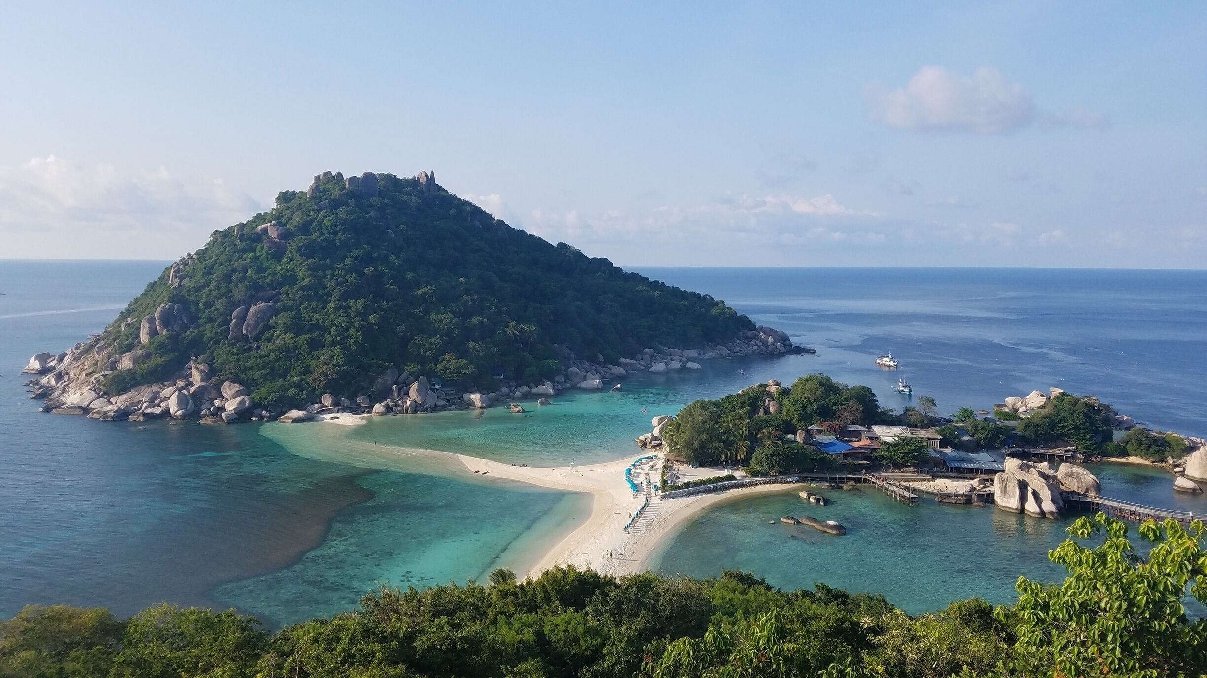 A tropical island with clear turquoise waters, a sandy beach, and lush greenery.