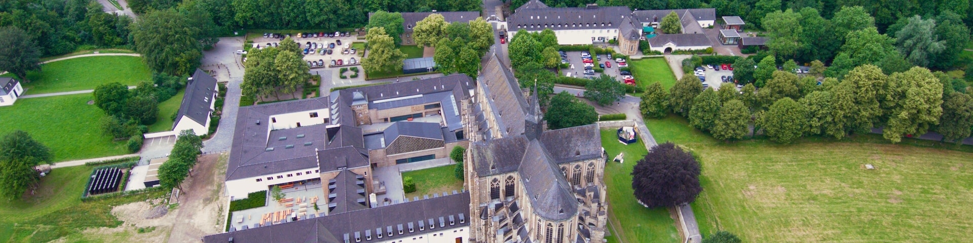 Vista aérea de un castillo histórico rodeado de abundante vegetación y edificios modernos.