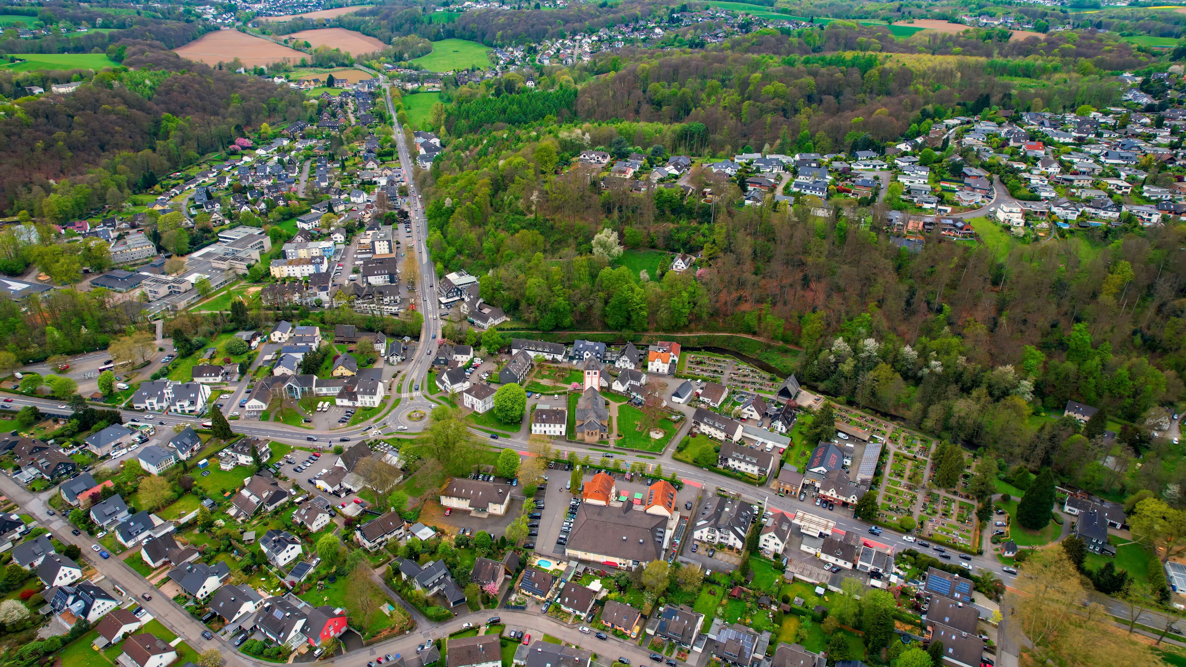 An aerial view of a residential area with houses, roads, and surrounding greenery.