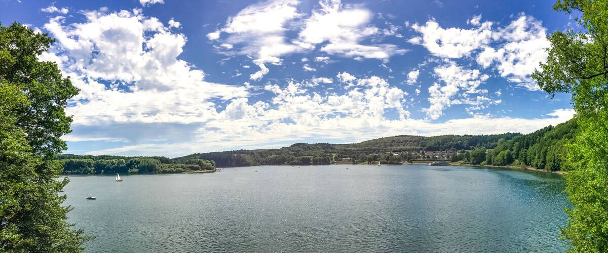 A lake surrounded by dense green forest and hills.