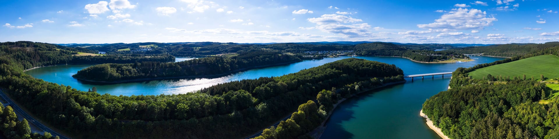A river winding through a forested landscape with a bridge over the water.
