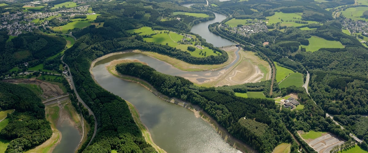 Biggevorsperre der Biggetalsperre mit Damm; links Dumicker Bach-Vorsperre; rechts Mitte am Ufer der Biggevorsperre Olper Ortsteil Eichhagen; Landesstraße 512, Bahnstrecke Finnentrop–Freudenberg; hinten links Olpe