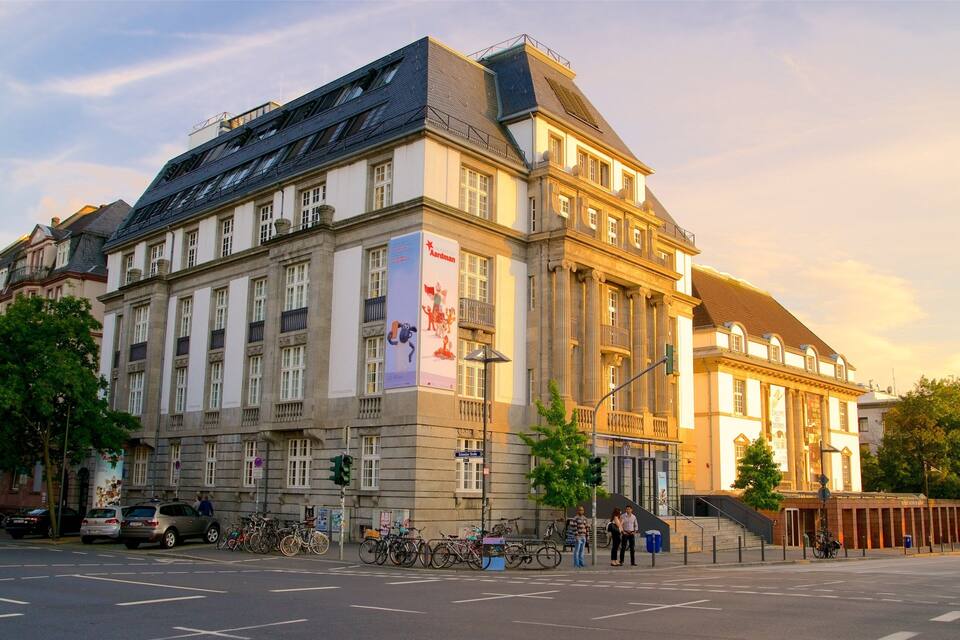 A historic building with a large banner, a staircase, and parked bicycles.