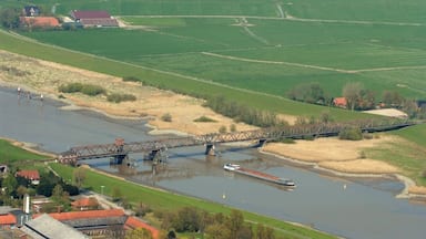 A river with a bridge, green fields, and a small boat.