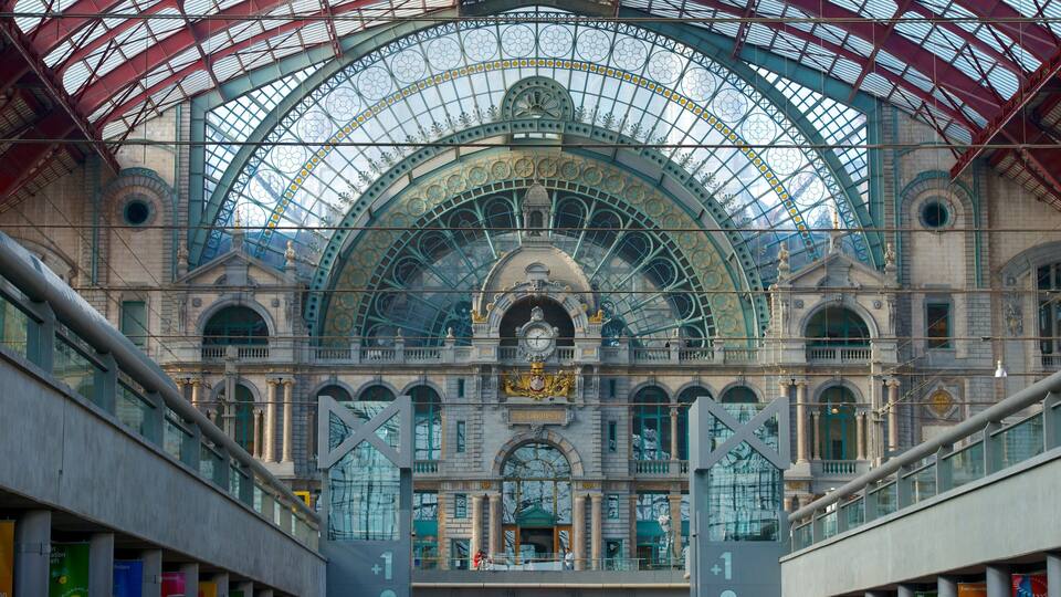 A grand train station with a large glass roof and ornate architecture.