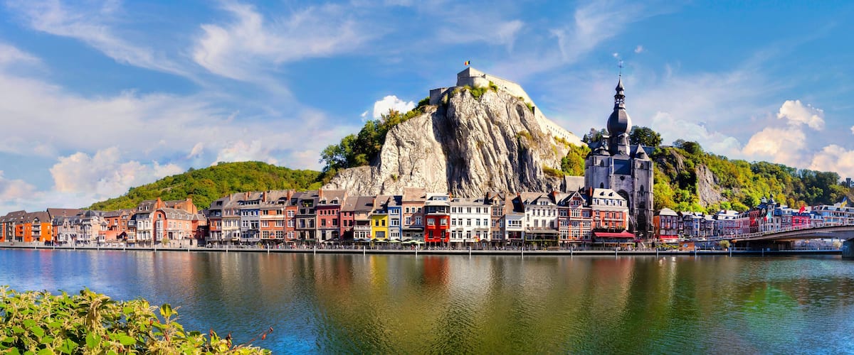 A river with a bridge, colorful buildings, and a prominent church on a hill.