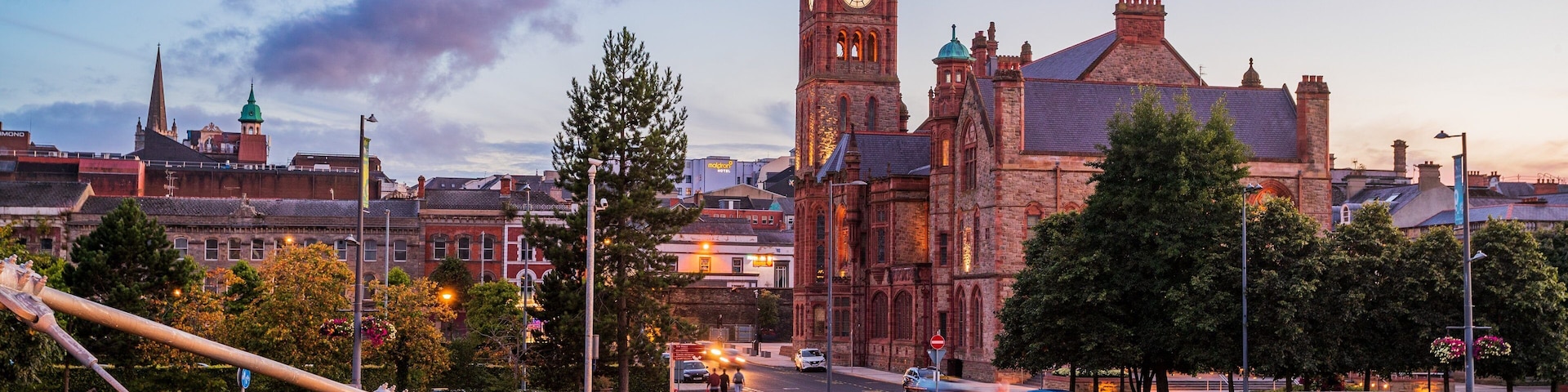 A bridge with a pedestrian walkway, a historic clock tower, and a cityscape with buildings in the background.
