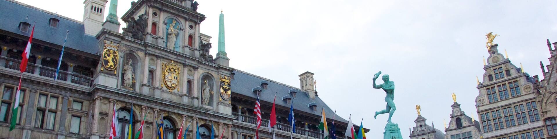 A historic building with multiple flags, a statue, and ornate architecture.