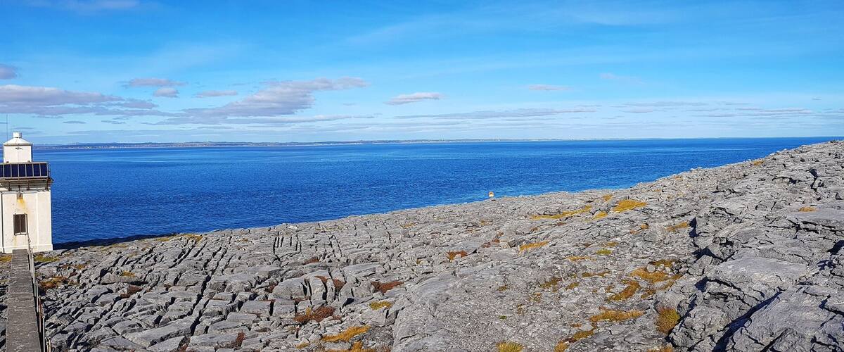 A rocky coastline with a lighthouse and the ocean in the background.