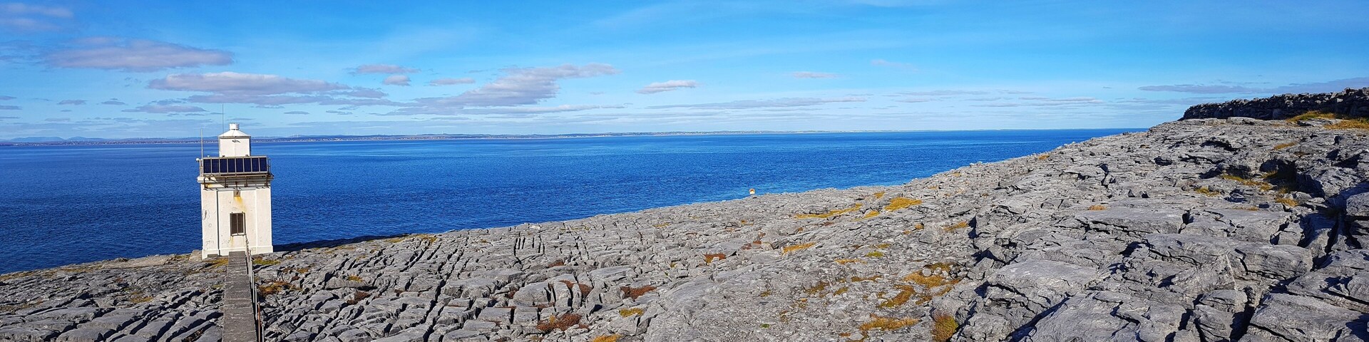 A rocky coastline with a lighthouse and the ocean in the background.