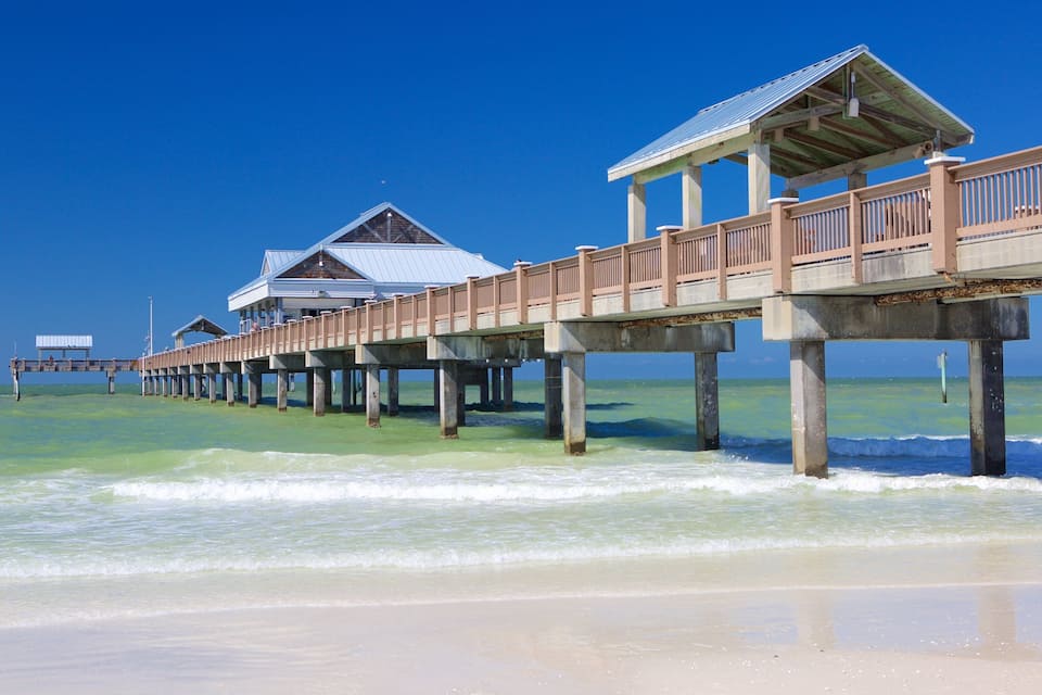 A wooden pier extending into the ocean with multiple buildings on stilts.