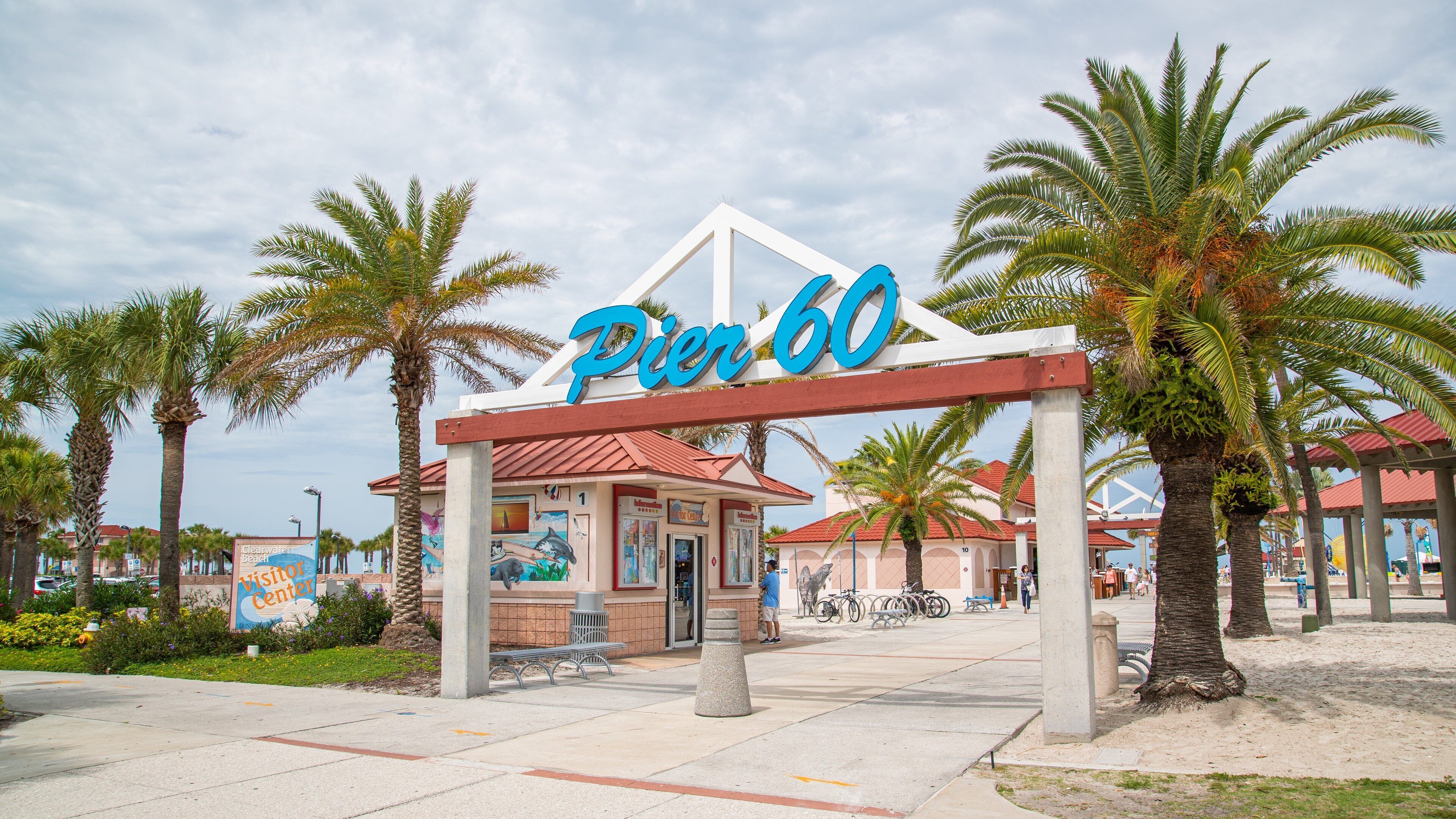 Pier 60 with a sign, palm trees, and a building with a red roof.