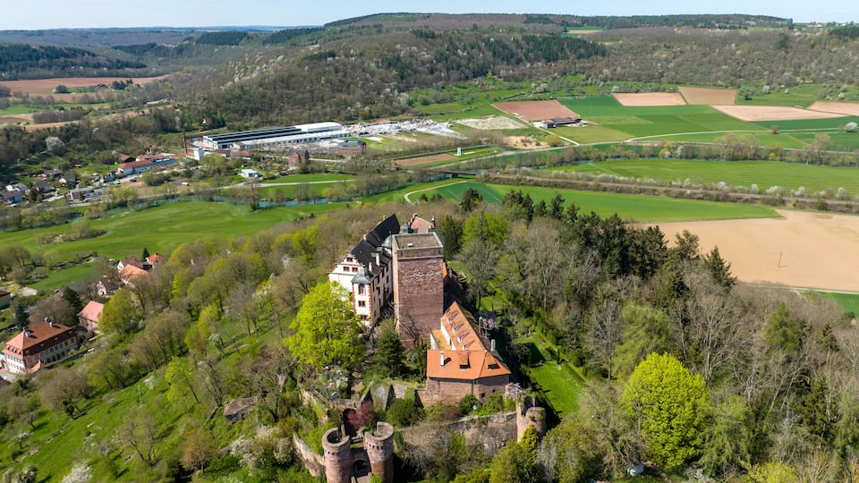 A castle surrounded by green fields and a modern building complex.