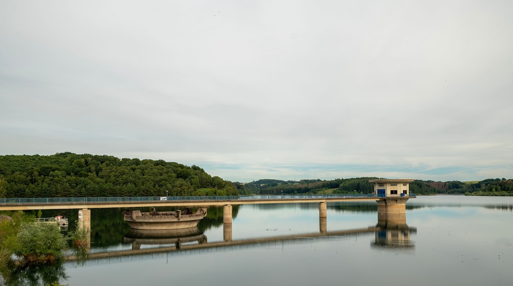 A calm lake with a bridge and a small building on stilts.