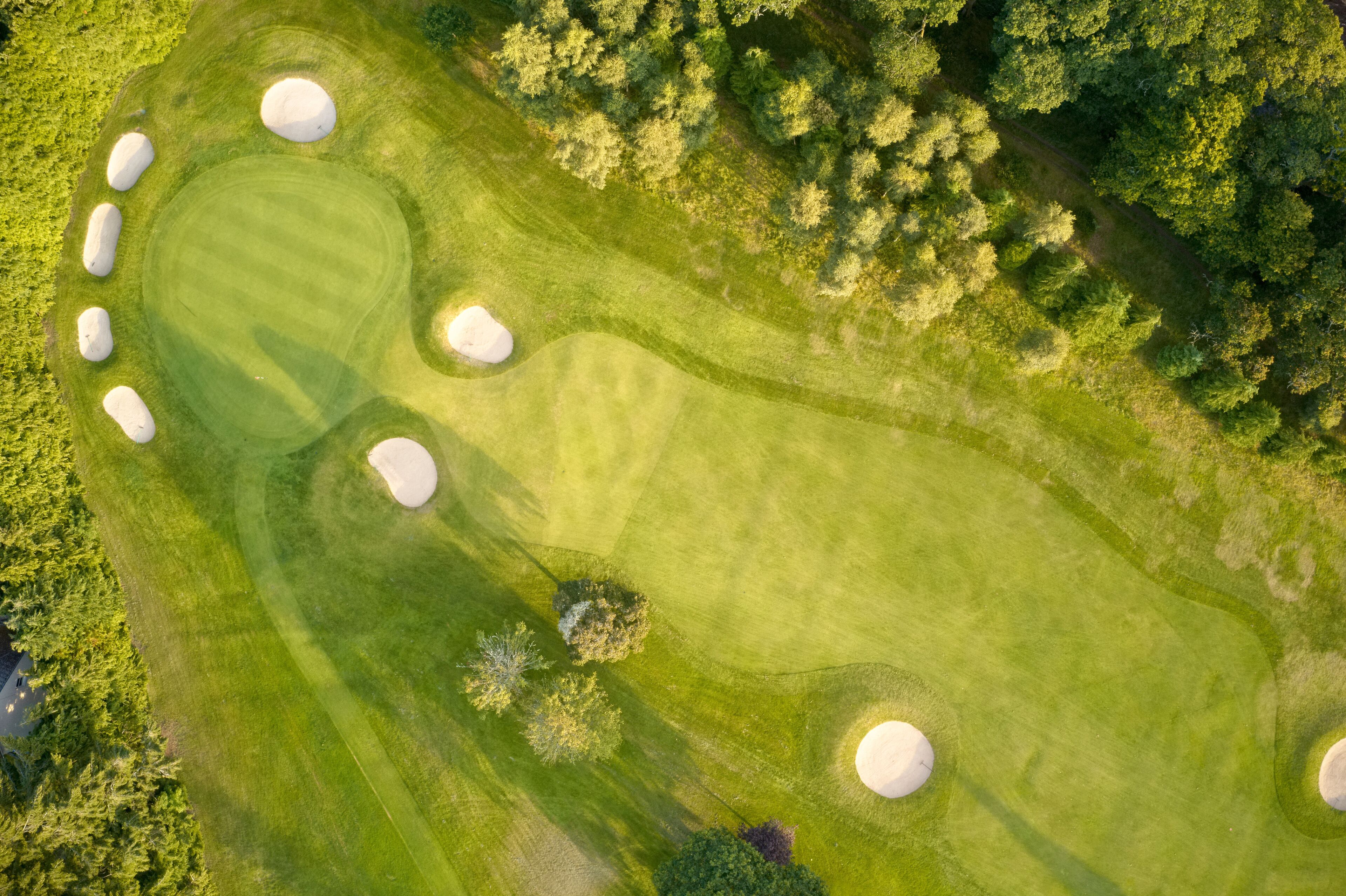 Aerial view of links golf course during summer showing green and bunkers at driving range