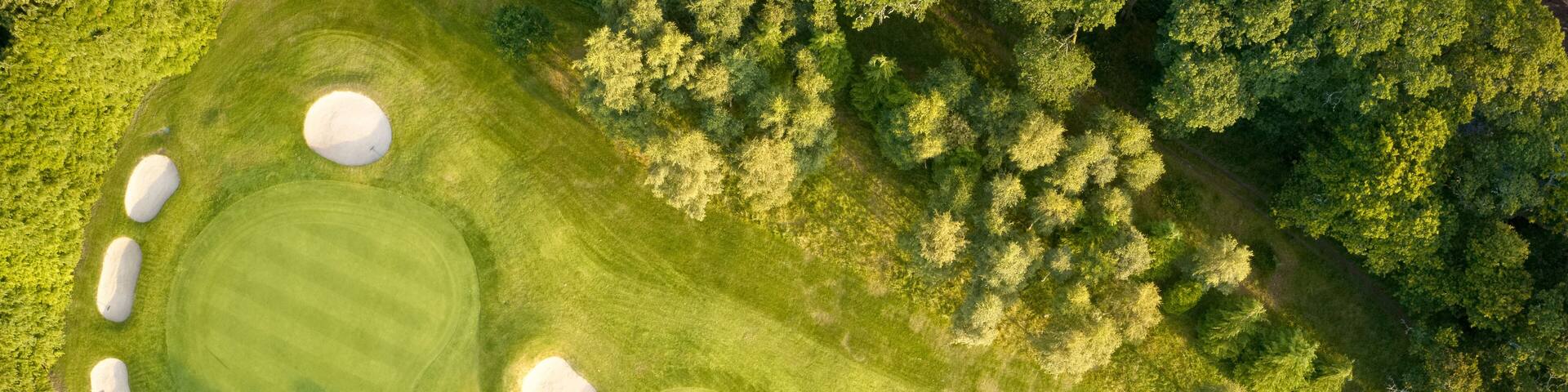 Aerial view of links golf course during summer showing green and bunkers at driving range