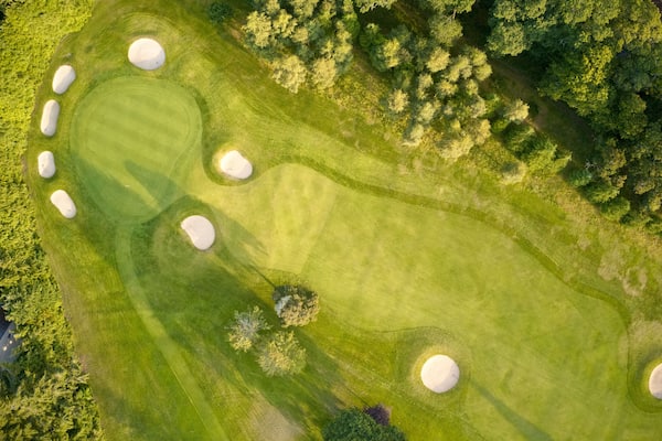 Aerial view of links golf course during summer showing green and bunkers at driving range